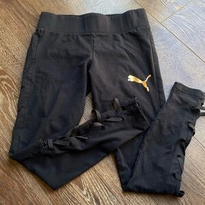 PUMA black leggings w gold metallic logo and lacing strappy details on calves